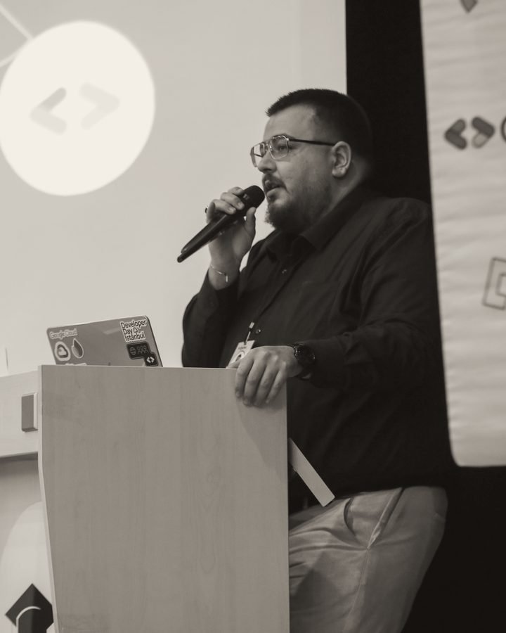 Berkay Geldeç speaking at a podium during a talk